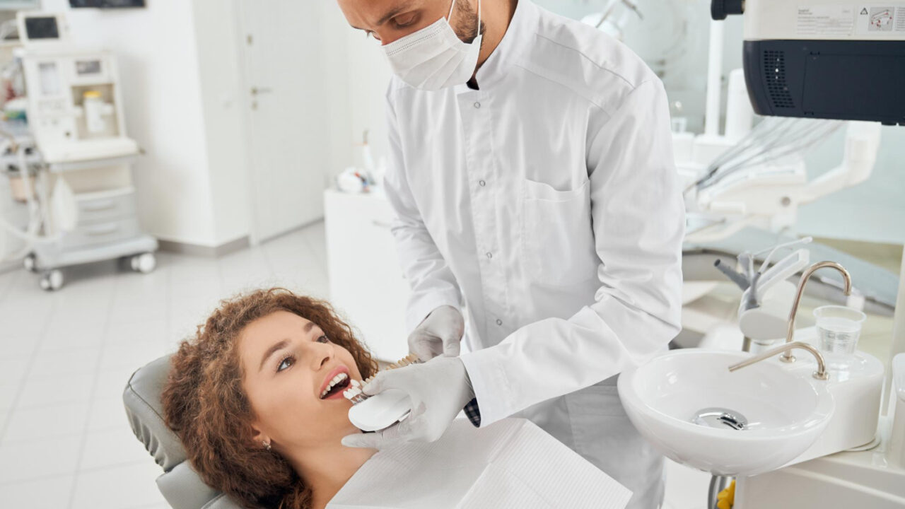 woman-smiling-while-male-dentist-keeping-teeth-color-range